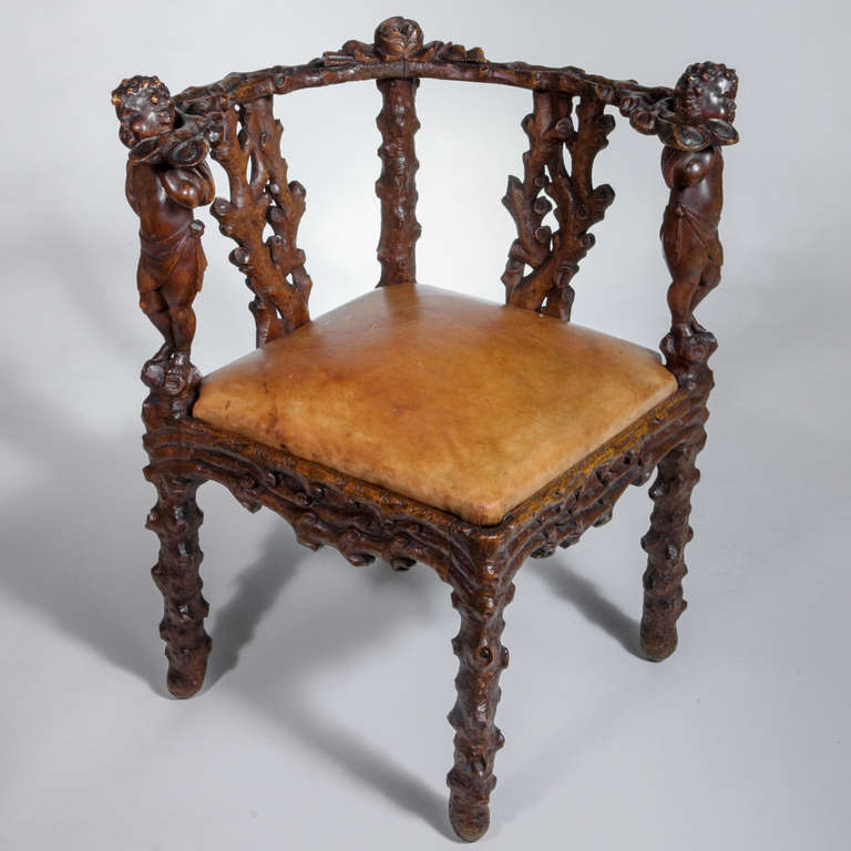 Fanciful 19th century Bavarian carved hardwood corner chair in a woodland design. Fashioned in a rustic twig pattern with carved leaves, acorns and small carved cherub heads on the arms. Leather insert seat.