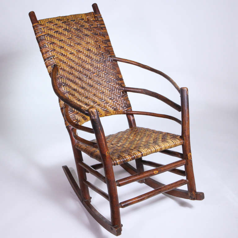 Outstanding high back Adirondack rocking chair with honey colored hardwood frame and woven seat and back. The arms formed with three curved birchwood pieces.