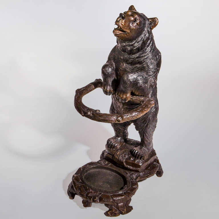 Carved Black Forest bear stick stand in the form of a standing bear perched on a rocky base. Strong depth of character face with roaring expression, traditional glass eyes, stained red tongue and rubbed nose. Fitted with original tin drip tray to