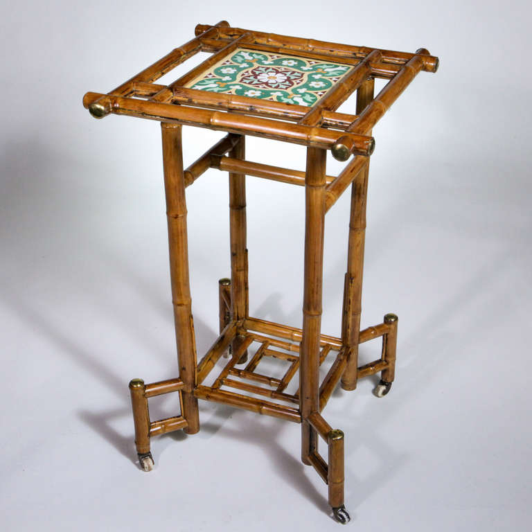 English bamboo plant stand with excellent detail and condition.  Upper shelf inset with multi-colored Moorish tile.  Traditional design with square shaped bamboo pieces.  The edges of the bamboo finished with brass caps.