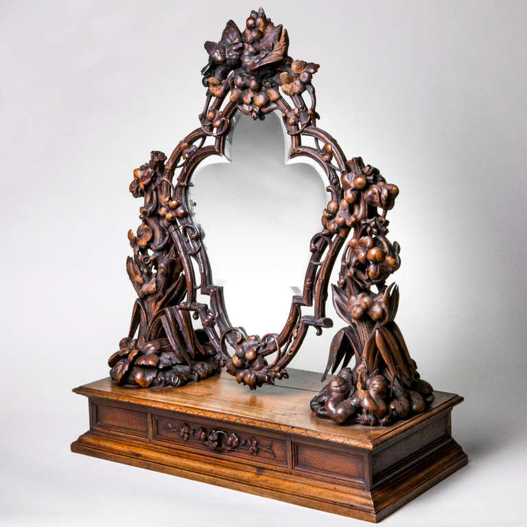 Miroir de coiffeuse bavarois en bois dur sculpté. Le miroir festonné est soutenu par un cadre en bois. Cadre et supports superbement sculptés avec des fleurs et des feuilles comme pièces latérales, un médaillon supérieur avec des oiseaux et des