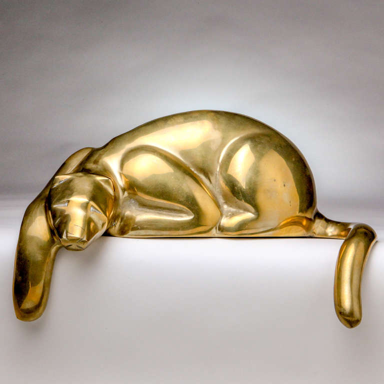 Vintage sculpted brass cat designed to sit on the edge of a shelf so that one paw and his tail hang down.
