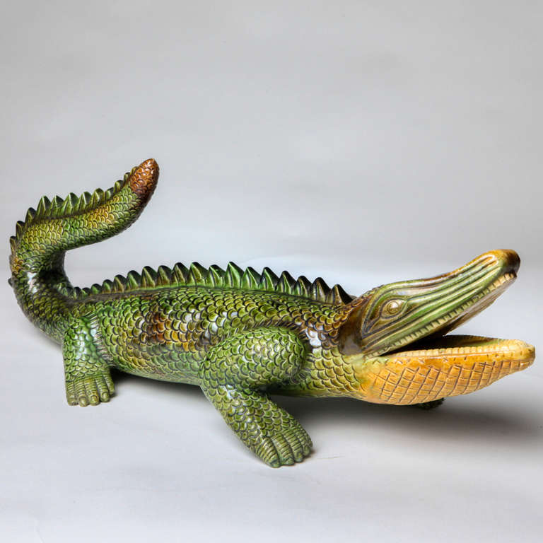 Large ceramic alligator in crawling stance with mouth open. Created with good detail and textured skin in strong Majolica colors of green, brown and blue.