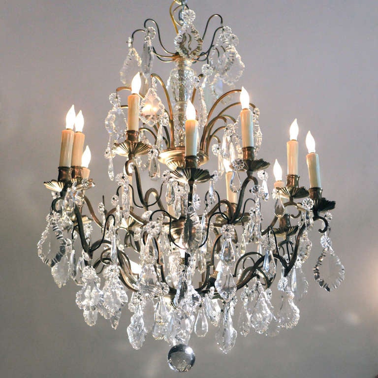 Four-tier crystal chandelier with bronze frame.  Twelve exterior lights and three interior uplights provide extra brightness and illumination.  Extra large hanging crystal plaquettes add luminosity!