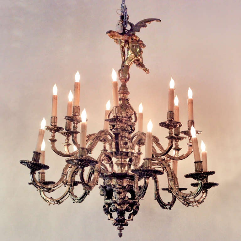 Exceptional Louis XVI French brass chandelier crowned by a robust cherub figure at the top. Ornately chased two-tier figural chandelier with detailed center column and eighteen 'S' scrolled acanthus arms. Baroque base of chandelier adorned with