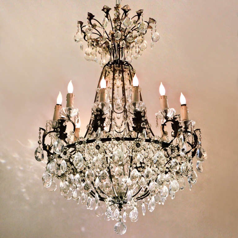 Magnifico lampadario a dodici luci in cristallo e bronzo in stile pompeiano. Cornice in bronzo pesantemente drappeggiata con perline di cristallo e innumerevoli rosette di cristallo. L'alto pezzo a corona con ampi dettagli in bronzo e cristallo, la