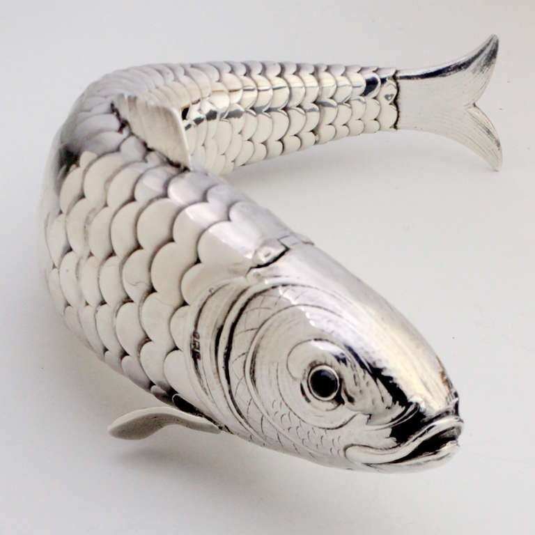 Hallmarked silver box in the form of an articulated fish with gemstone set red eyes. Hinged head and mouth open to hold trinkets or spices.  Piece has both French and English hallmarks. Hallmark on head: London, 1902-3. 