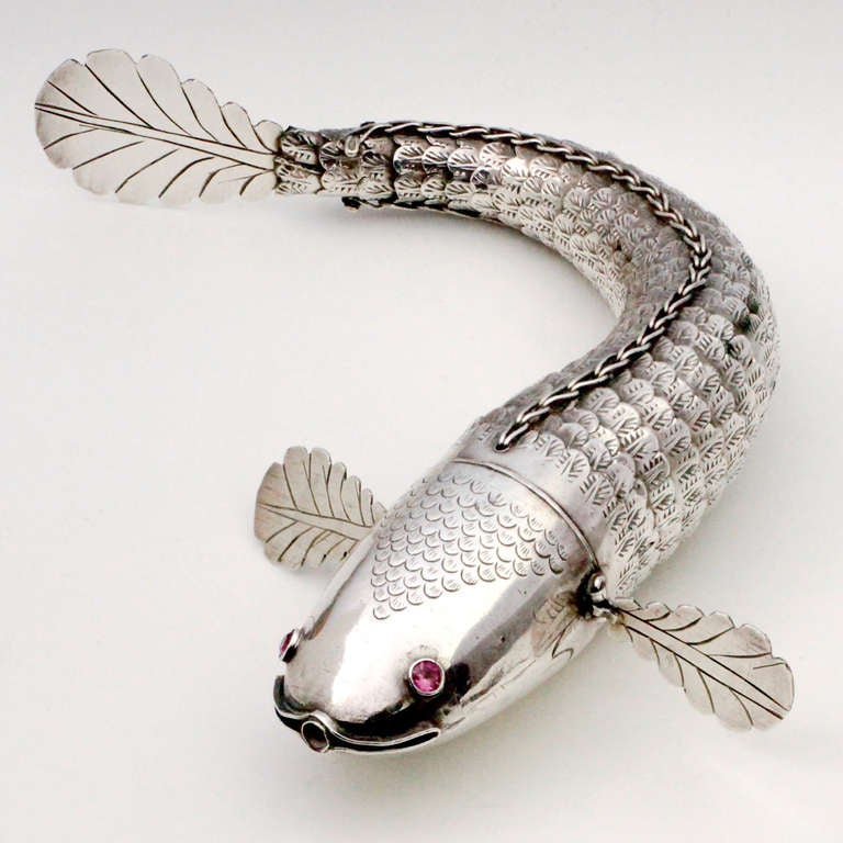 Finely articulated silver fish with gemstone set pink eyes. Beautifully engraved details on head, scales, gills and tail.