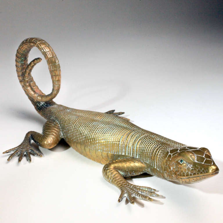 Large antique brass lizard finely detailed with realistic scales, web feet, and green garnet eyes.  In a life-like natural pose with curled tail.