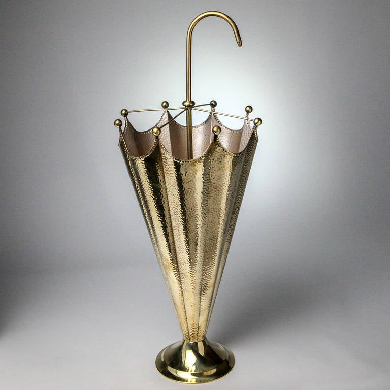 Brass umbrella stand with pebble finish. Shaped like a partial open umbrella with a curved handle.