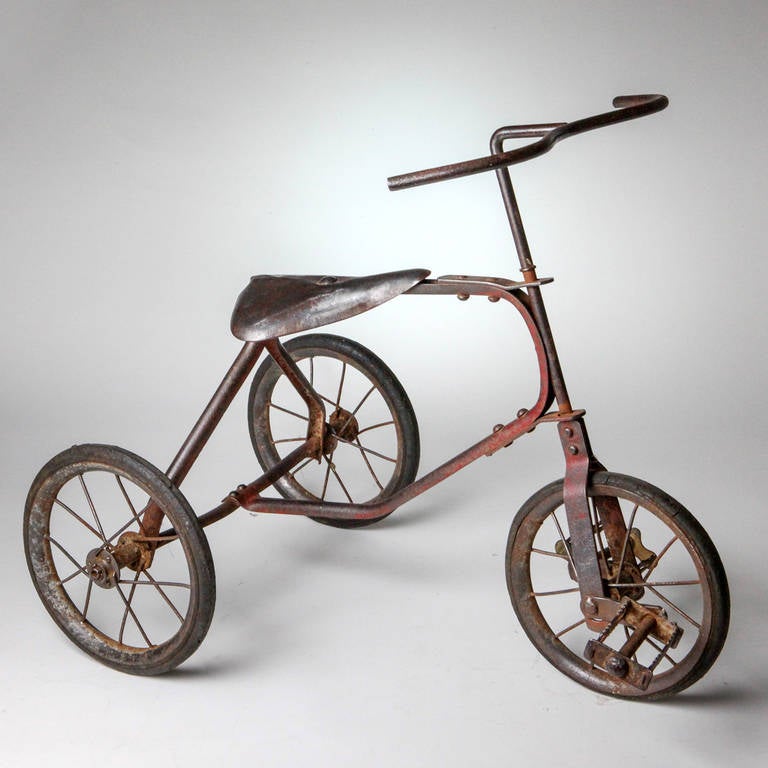 Vintage French child's tricycle with hollow metal frame and metal pedals.