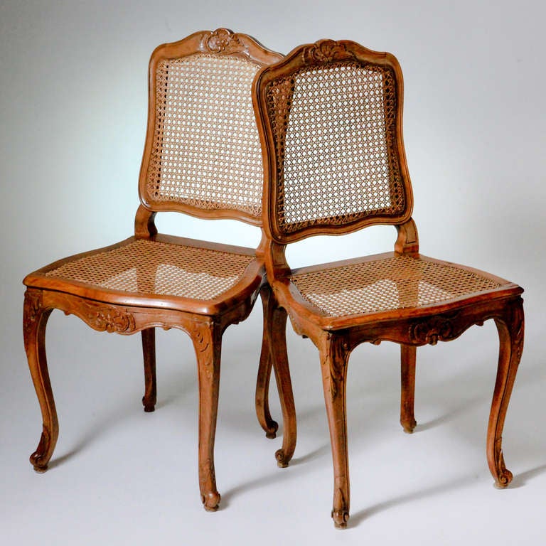 Set of two French Louis XV carved beechwood side chairs with caned backs and seats on cabriole legs. The chair front and crest rail with carved flower and scroll design. Two additional chairs available.