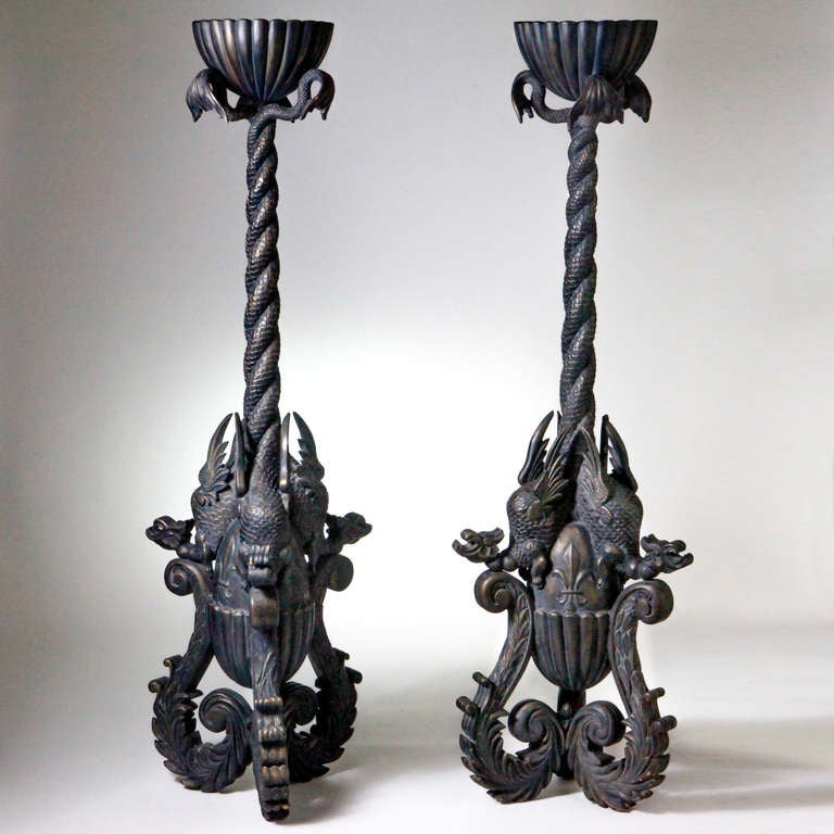 Dramatic early 19th century pair of seven foot tall French torcheres that were made for a theater in Normandy. Intricately carved wood pieces designed with oversized scrolled bases that surround a center acorn shape with fleur-de-lis detail. The