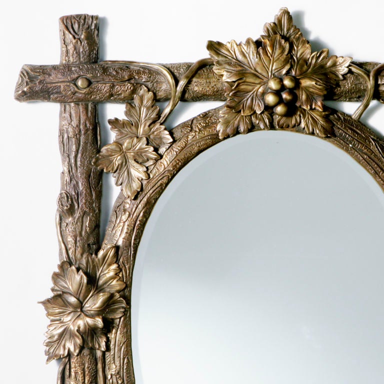 Exquisite rare antique bronze mirror with a woodland theme of twigs, branches, leaves and berries. Beveled oval mirror.