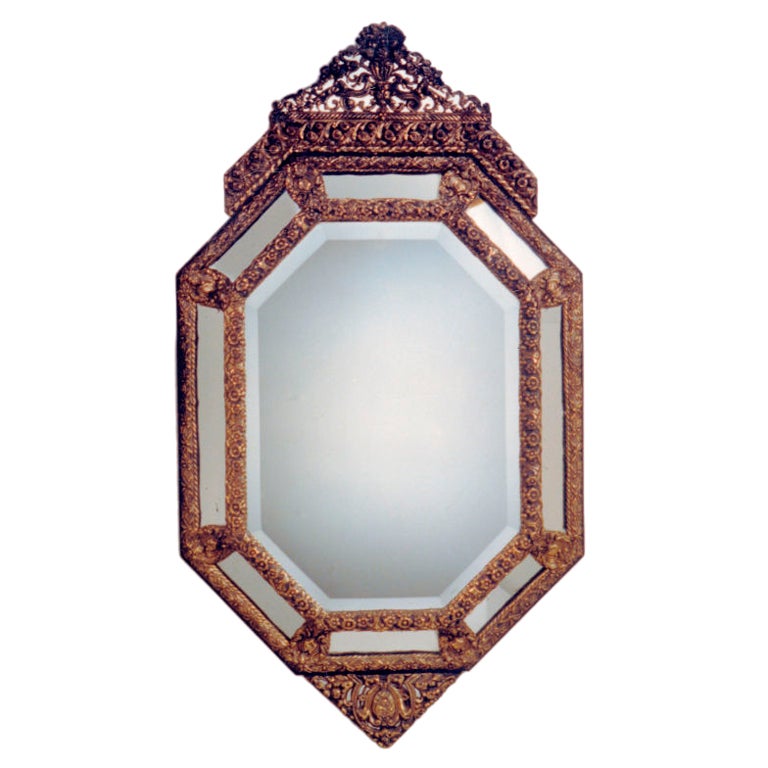 Miroir octogonal à coussin avec cadre en laiton repoussé et couronne triangulaire, tablier à motifs floraux.