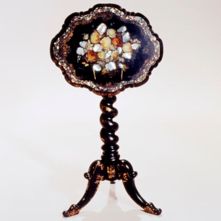 Victorian black lacquer music stand on bold twisted column tripod base. Tilt-top inlaid with mother-of-pearl and painted in flower pattern, edged in gilt.