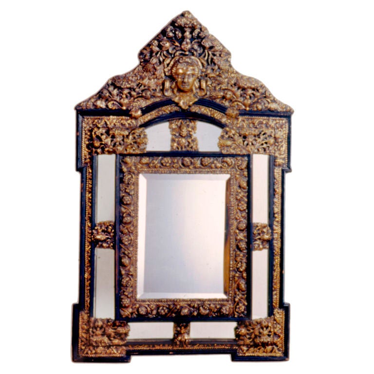 French brass and wood repousse cushion mirror with arched crown featuring Victorian female face, garlands and floral motifs.
