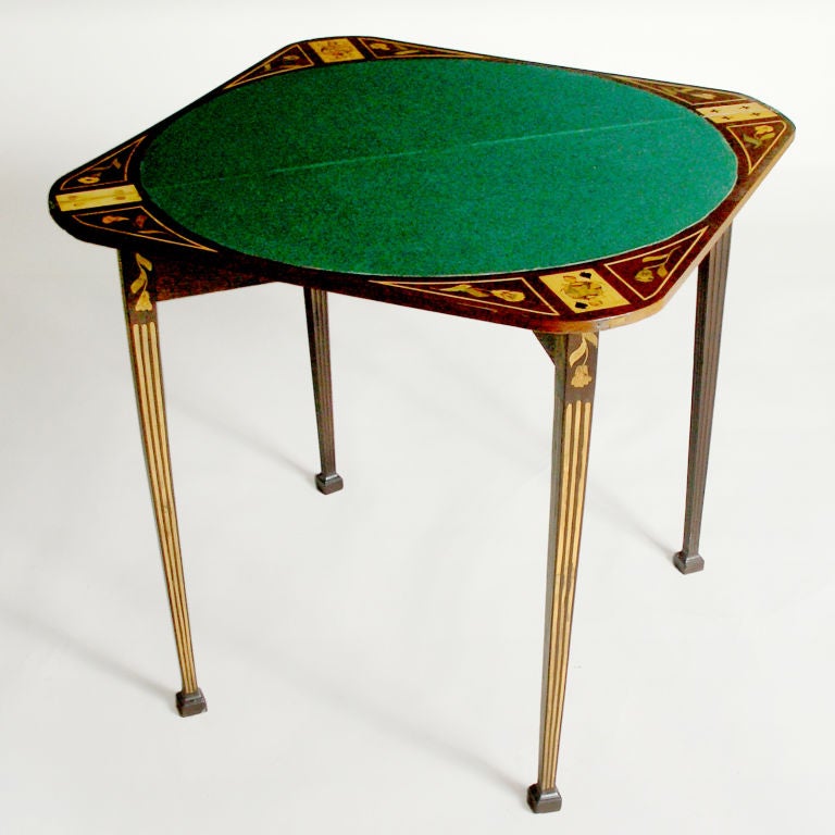 Dutch marquetry game table inlaid with floral pattern. When open, table has green felt circle with inlaid playing card pieces in each corner. Table folds to drop-leaf triangle for storage against wall.