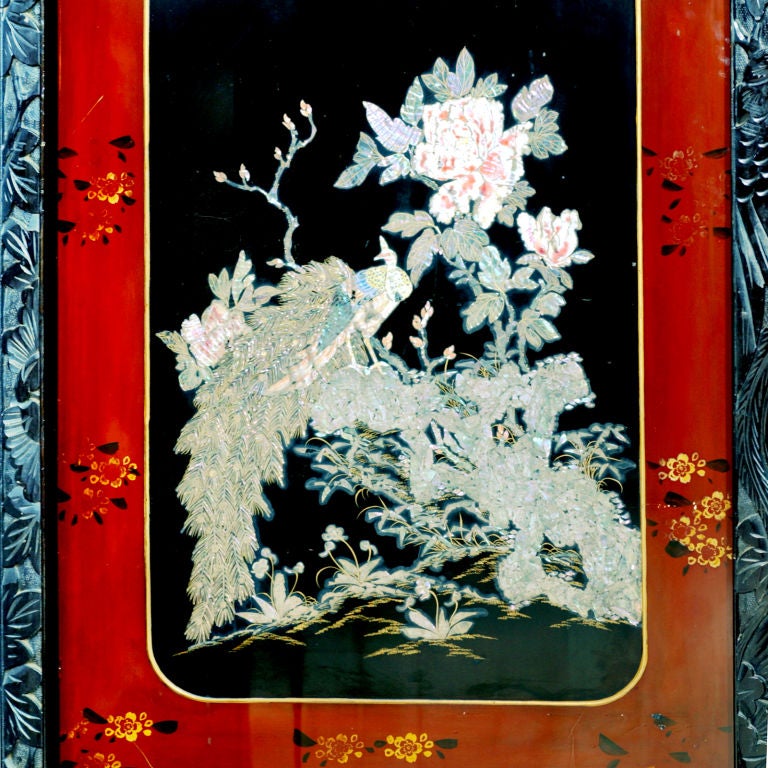 Beautifully carved Oriental bi-fold screen.  The ebonized wood frame intricately carved with a large bird and leaf design that is continued down the sides and onto the bottom panel.  The lacquered center panels applied with an ornate mother-of-pearl