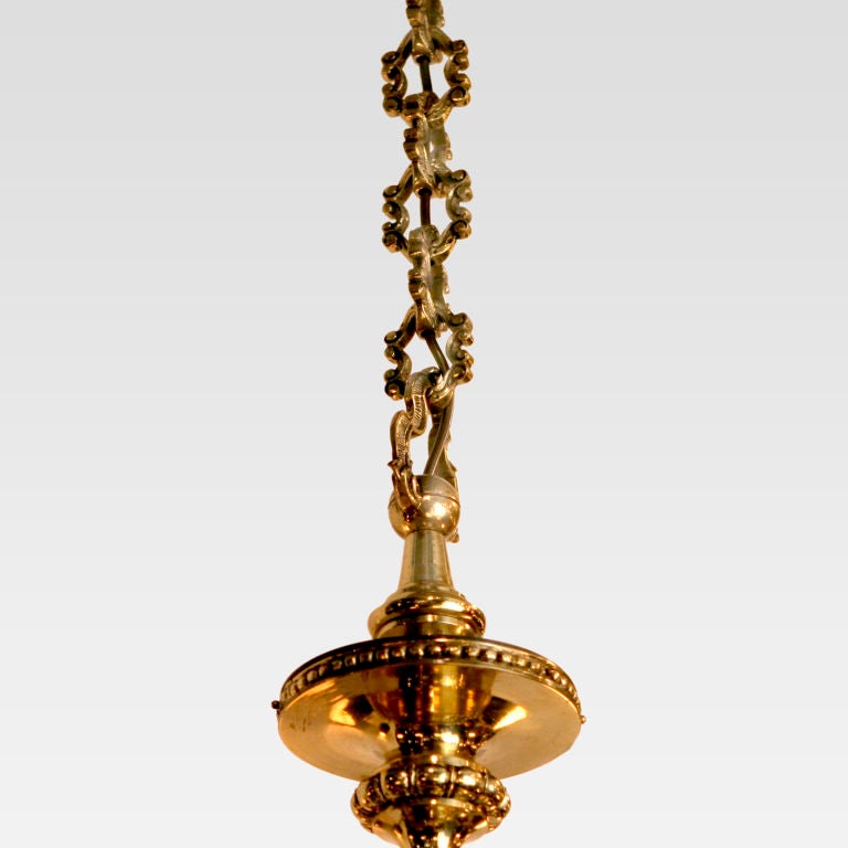 Impressive Irish brass chandelier with eight double-scrolled arms arranged in a single tier around an urn-shaped center. The central column swirled and beaded with an acanthus leaf design on the shaped bottom finial. Features the original decorative