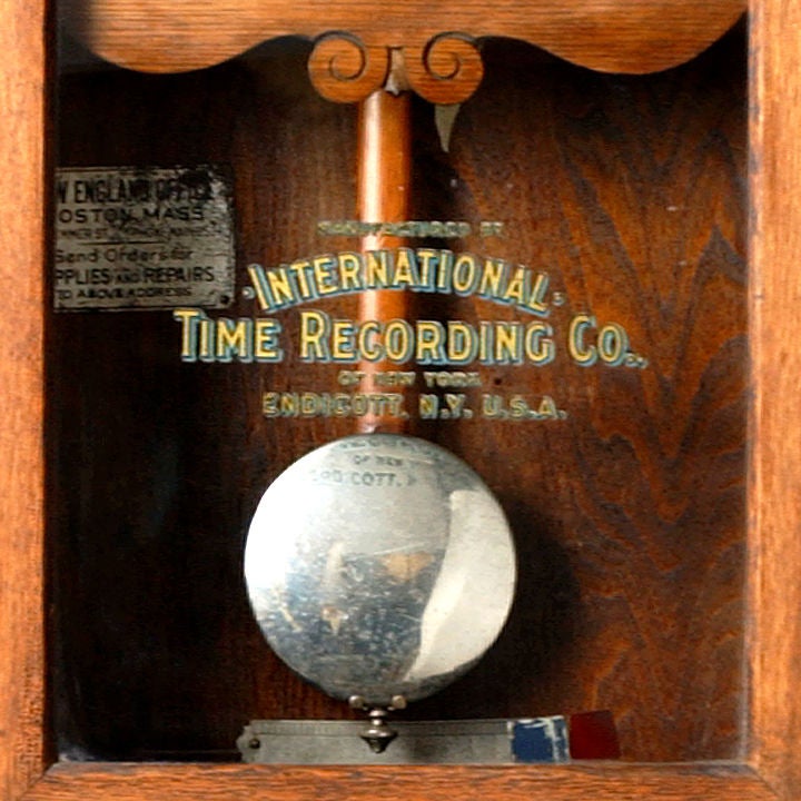 Punching in wall-mounted time clock in oak case. Marked: International Time Record Co., Endicott, NY, USA. Endicott is best known as the birthplace of IBM. The Computing Tabulating Recording Corporation, International Time Recording Company and