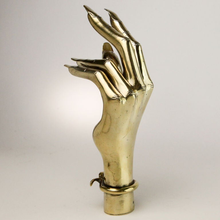 Exotic representation of a female hand, popular in Victorian times as a desk object or a decorative accessory.  Expressive life-size brass model complete with long fingernails and twisted metal bracelet.