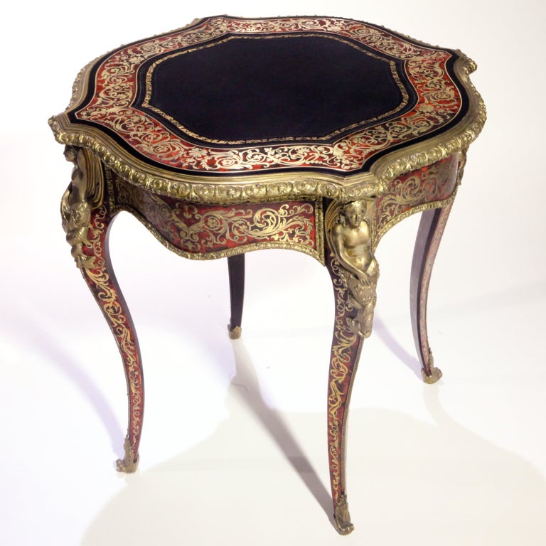 Boulle serpentine center table intricately inlaid with cut brass. Black tooled leather top with brass female figural mounts on cabriole legs.