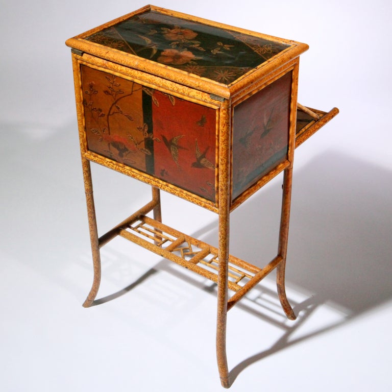 Beautiful quality 19th century English bamboo sewing table.   Victorian design – the top opens to reveal a large box with rose red quilted interior; the front panel drops down to form a work space shelf; and there is a hidden storage shelf.  It is
