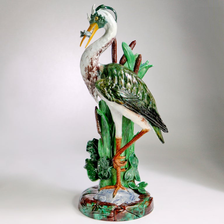 Large size Holdcroft heron flower stand. The heron with gray fish in his beak, chest with brown and white coloring. Standing on a gray rock with a green and brown wide rocky base. Impressed: Holdcroft. Marked: three dots & 8, circa 1875.