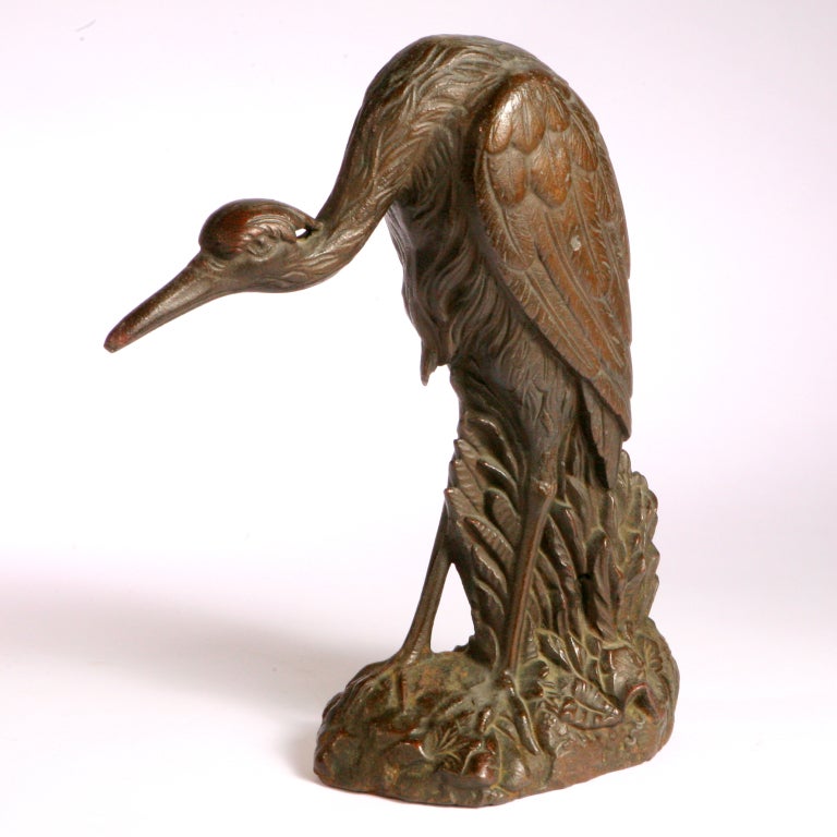 Realistically portrayed pair of bronzed cast iron heron figures. Each naturally sculpted standing on a leafy base.