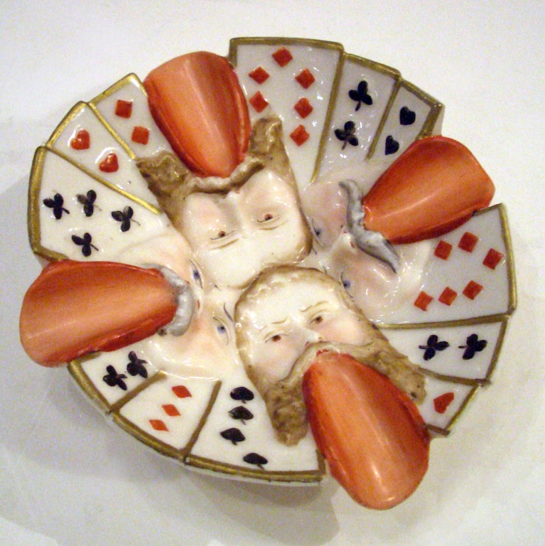 Whimsical early 20th century German porcelain ashtray with playing card motif.  Designed with the cigarette holders as faces with tongues sticking out.  Stamped and numbered.