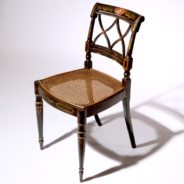 Nicely detailed black lacquered Regency style chair with x-cross back splat, hand-turned frame and front legs.  The entire chair painted with leaf, scroll and bead work detail using bronze powder. The faded back frieze with a center medallion