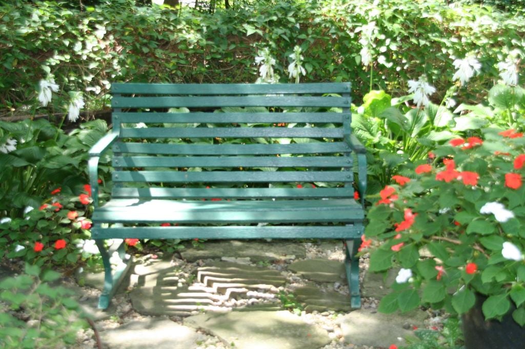 A small American garden bench, wood slats and iron supports painted in  forest green.

