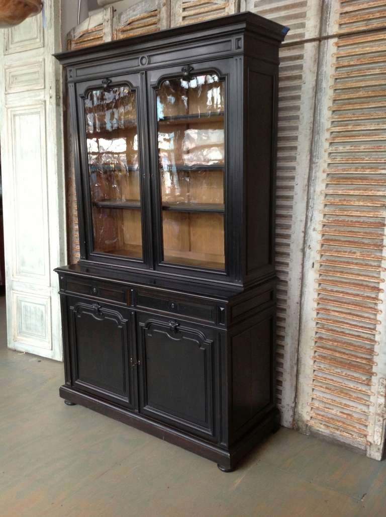 French Napoleon III ebonized bookcase with original glass doors. This piece is in two parts with the lower case has solid doors. The top  compartment has 3 adjustable shelves and the bottom has 1 shelf. The bookcase is in good vintage  condition and