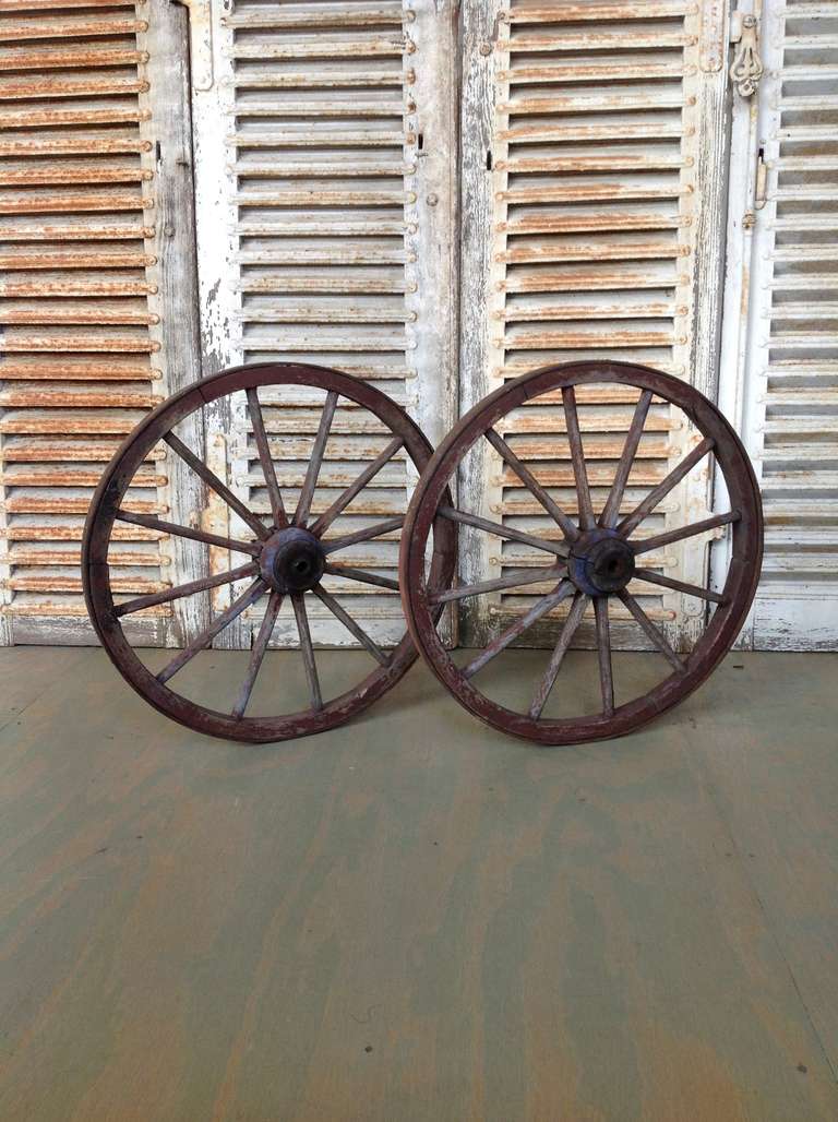 A pair of French 19th century wooden dog cart wagon wheels with iron bands. These wheels are for rental only.