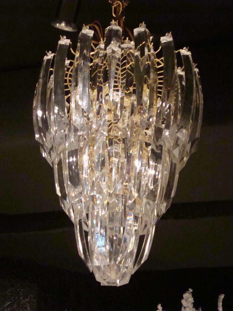 Glamorous three tiered curved cascading acrylic chandelier.  Gold metal base with circle of 6 lights at the top of the frame.  Clear acrylic asymmetrical wedges.

36