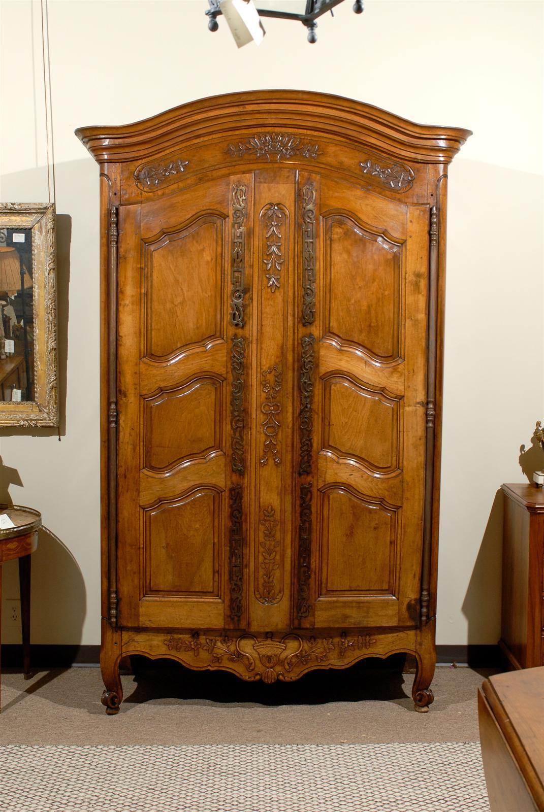 This is a finely carved French armoire in solid walnut.  It is late 18th century from the Provence region.  Details include three paneled doors, a classic curved top, and elegant scroll feet.  The original iron hardware adds to the overall design.