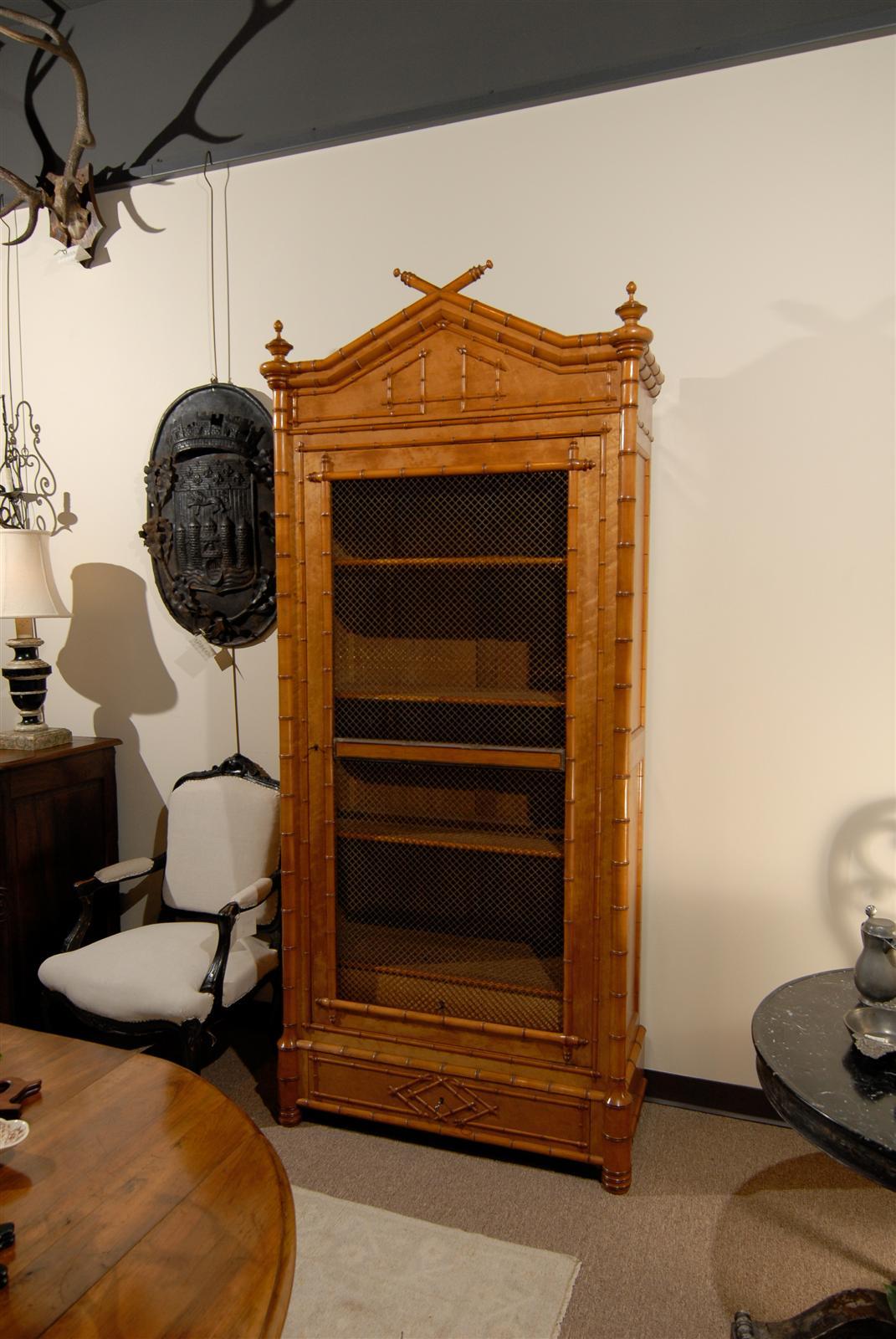 This was a popular style in the late 19th century and usually had a mirror in the door.  In this case the mirror has been replace with brass mesh which is a big improvement since the mirrored doors tended to be extremely heavy and somewhat