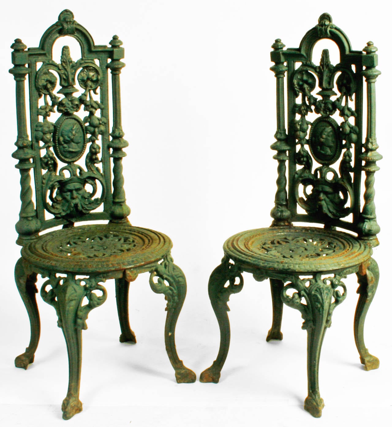 Pair of Victorian finely cast iron and green painted garden chairs. The chair backs are decorated with a central medallion of Aphrodite the Greek Goddess of beauty. She is surrounded by scrolling leaves, cascading fruit and Father Wind. The seats