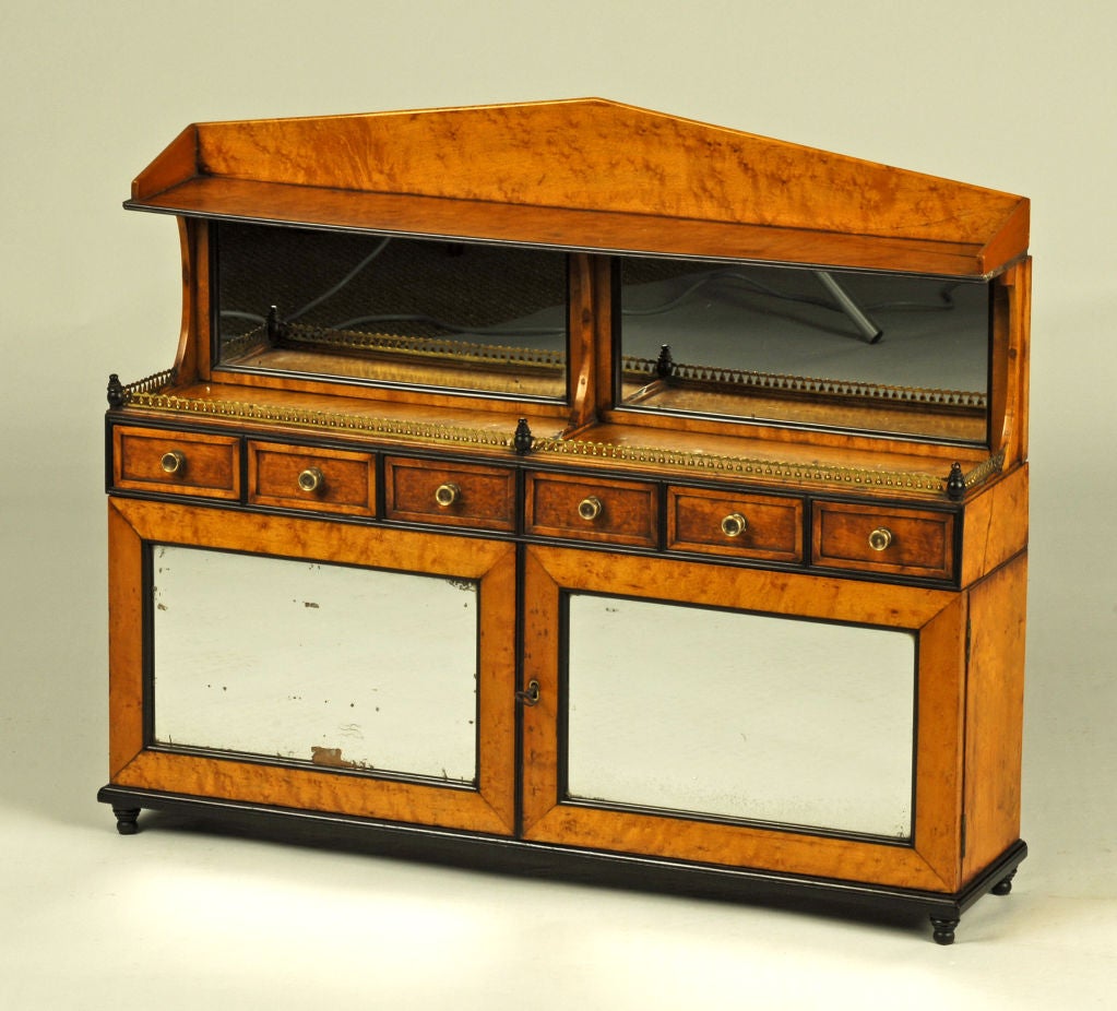 Miniature English Regency chiffonier, c1810, the shaped cornice supported by a pair of mirrors over a pierced brass gallery, the lower section fitted with six drawers and six interior shelves behind two mirrored cabinet doors, in bird’s-eye-maple