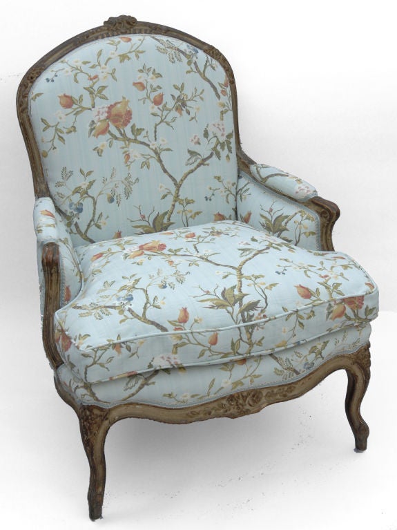 This French Bergere has the typical carved details of Louis XV period. At the center of the  crest rail are carved roses with trailing leaves and ribbons. The rose motif appears at the corners of the back rail, the stretcher and on the chairs
