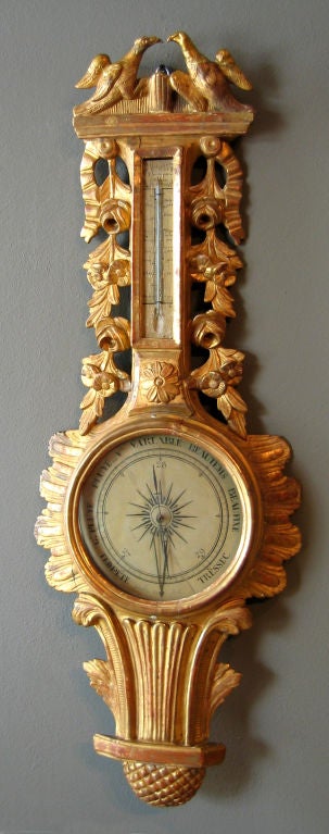 French giltwood barometer with love bird finial above the thermometer, carved with railing roses and a stylized ribbon. The barometer face is set within a border of petals over a tapering throat above a pinecone drop.