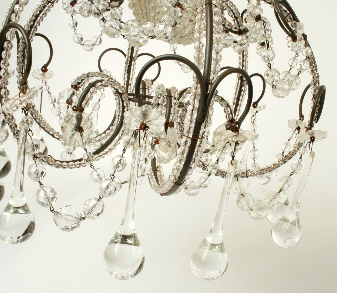 This pretty French crystal chandelier has a scrolled metal frame with varied tear drop and floral crystals. The frame is covered in linked faceted crystal beads, graduated swags and a removable crystal light bulb sock. A pretty touch for a smaller