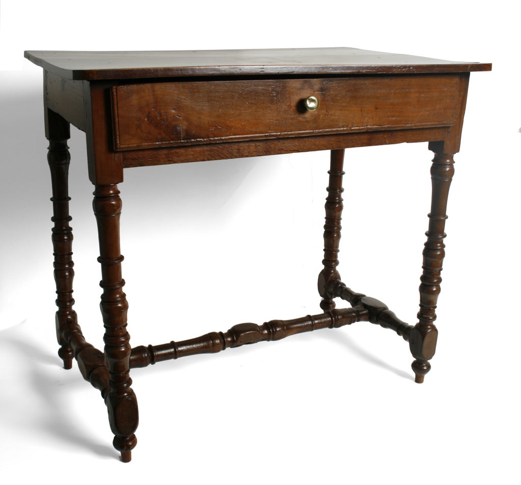 This rectangular French table has the warm and mellow color of aged walnut. It has one drawer with a brass pull. The table stands on beautifully turned legs and stretchers. A great side table or bedside table.