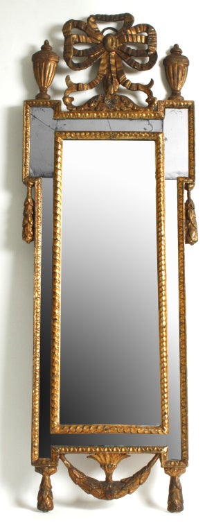 This Italian mirror circa 1790, has beautiful detailing. The center plate is surrounded by a mirrored frame with classical egg-and-dart rope moldings. At the top of the mirrored frame stands a bow of gilt ribbons flanked by a pair of classical urns.