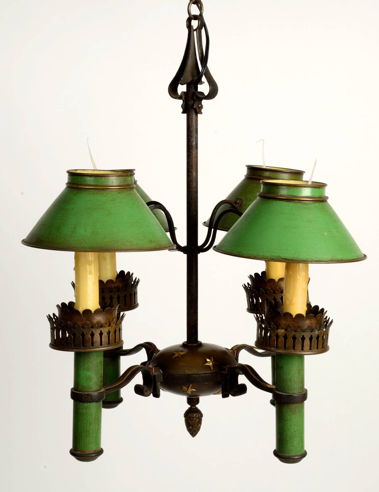 Painted tole and brass four-light chandelier, early 20th c. The chandelier has adjustable height shades. The body is of patinated brass with gilt brass stars on the top and bottom of the brass body. The shades and candle stems are green painted tole