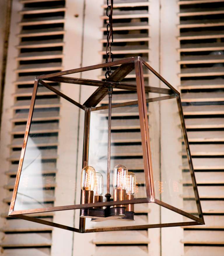 Large darkened brass and glass lantern of a simple and elegant design.
Made by hand in the USA, newly wired with four Edison sockets. Handcrafted brass cluster with brass candle sleeves. UL listed for dry Locations. Available in clear or wavy