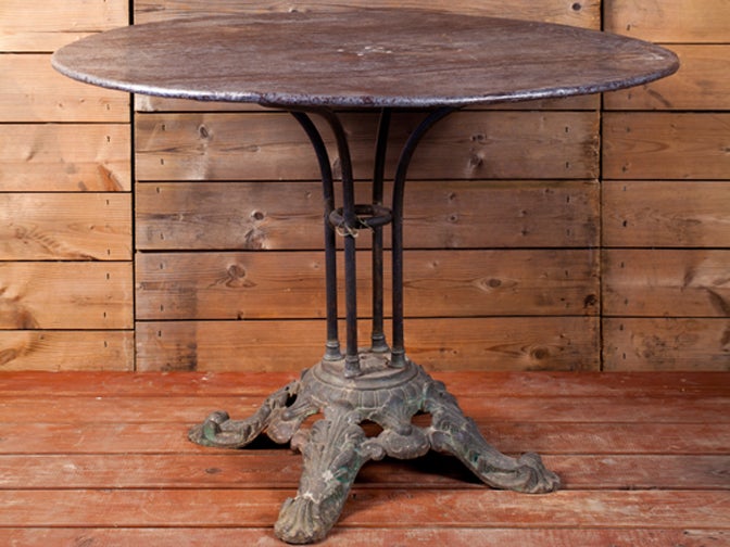 Antique table with an iron top and beautiful cast iron base with four feet. From France, circa 1890. At sometime, the top had an umbrella hole which has been filled in. Unusual in its larger size.