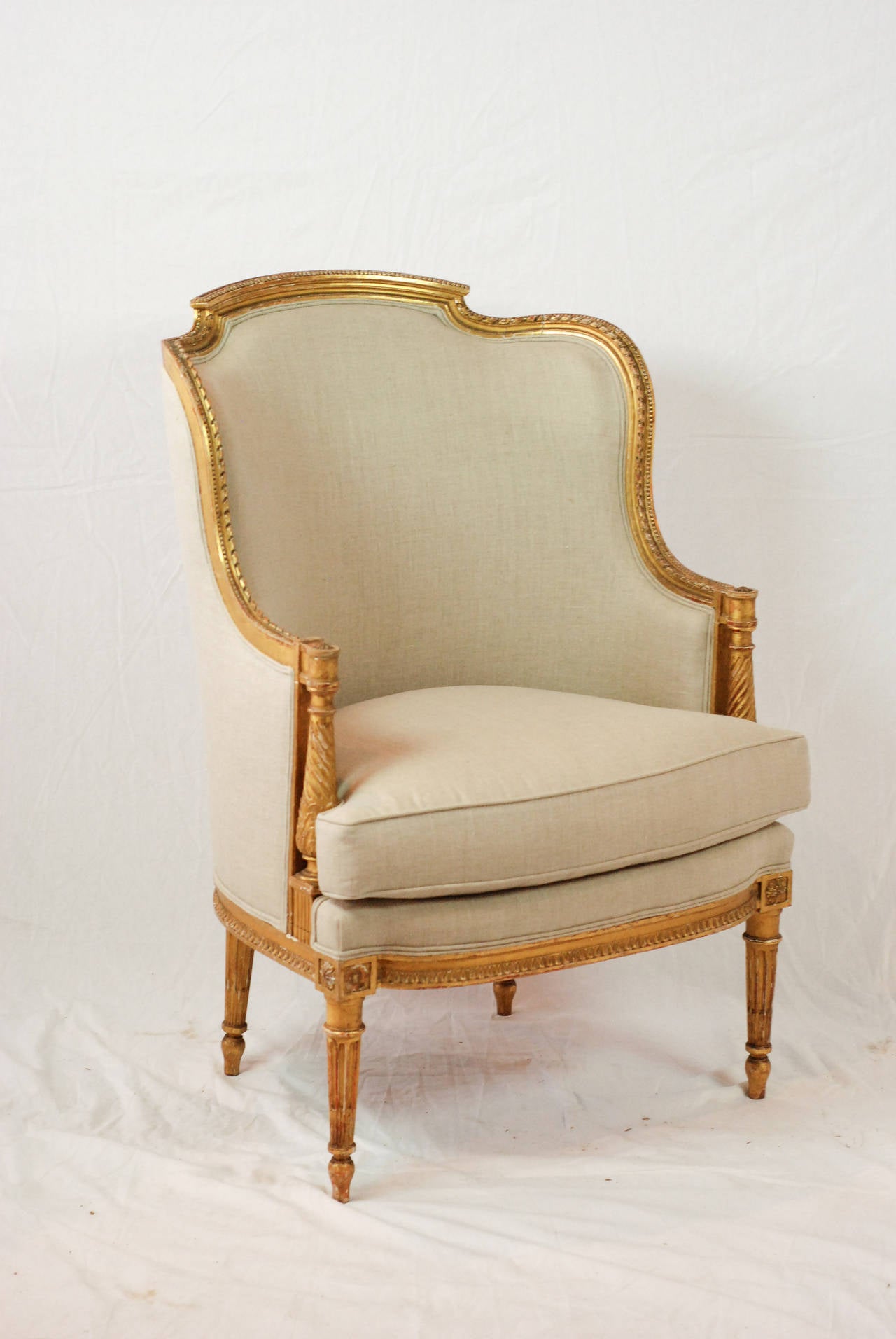 19th century Louis XVI gilded armchair with rounded back, new cushion and newly upholstered in linen.