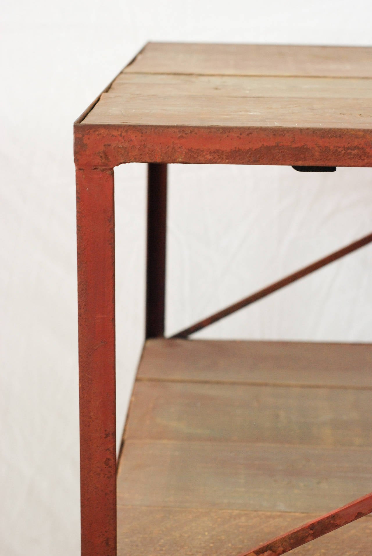 19th century two-tier work table of red iron and pine planks on wheels.